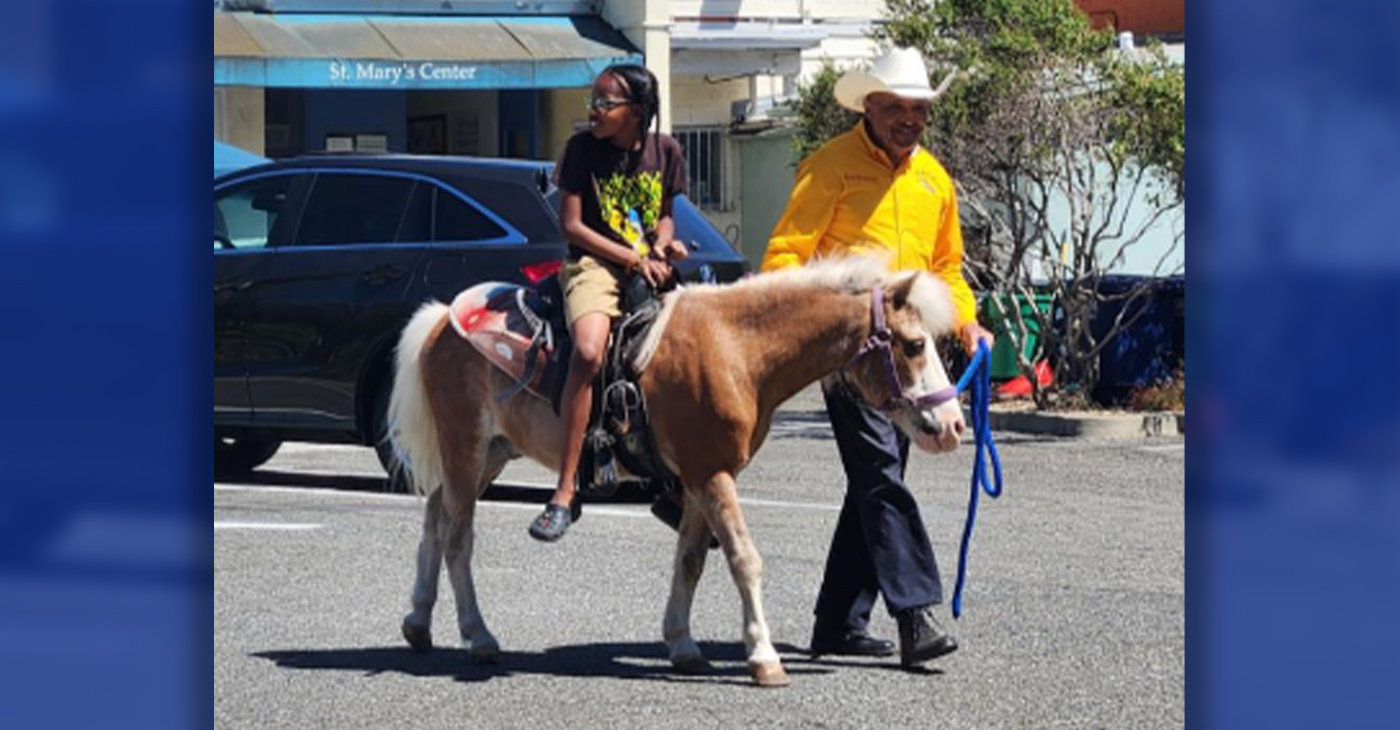 Oakland Black Cowboys Association President Wilbert McAlister leads a girl on a pony ride at the B-H Brilliant Minds Juneteenth. Photo by Daisha Williams.