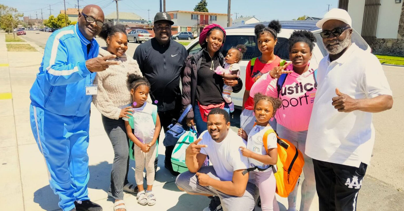 Rev. Andre Shumake, far right, and Antwon Cloird, far left, pose with recipients of the back-to-school supplies. Photo by Mike Kinney.